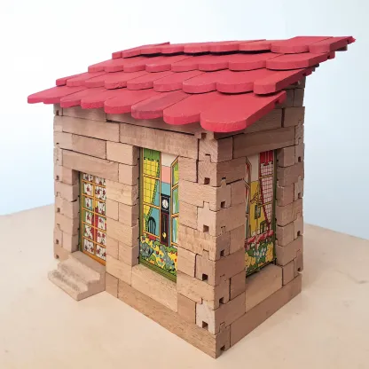 Kleines Haus aus hölzernen Steckbausteinen mit rotem Ziegeldach und bunten bedruckten Fenster-/Türpaneelen, Vintage-Baukasten.