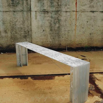 Minimalistische Sitzbank aus Metall vor einer rohen Betonwand, modernes Designobjekt in industrieller Umgebung.